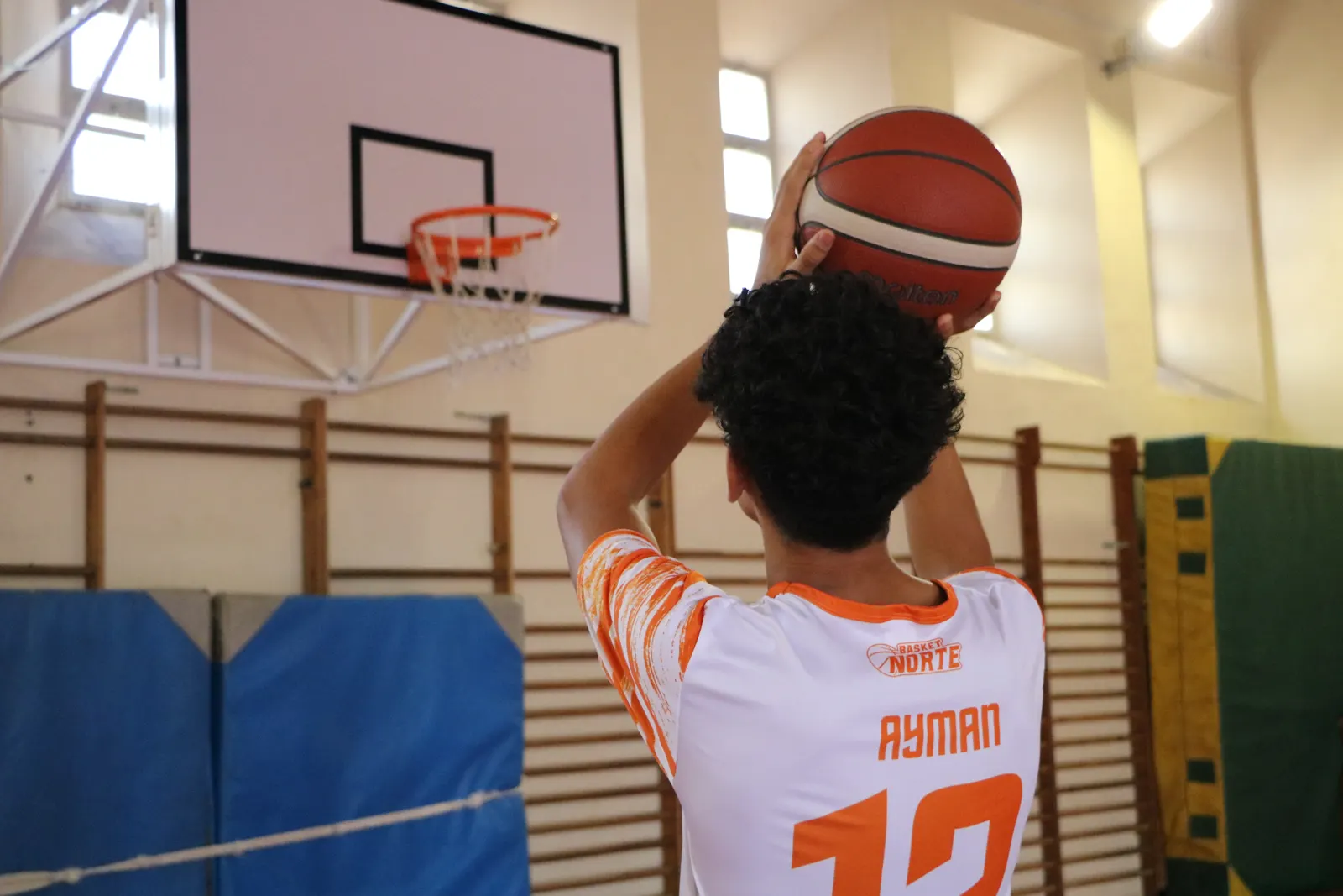 Jugador lanzando a canasta en el gimnasio